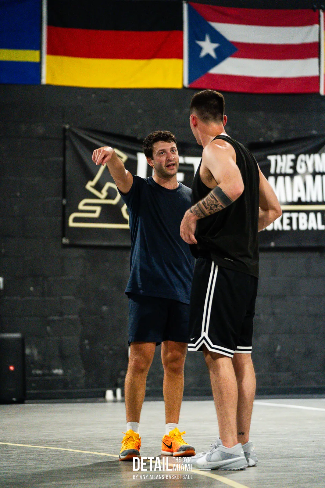 Two players talking on court under the DETAIL Miami banner